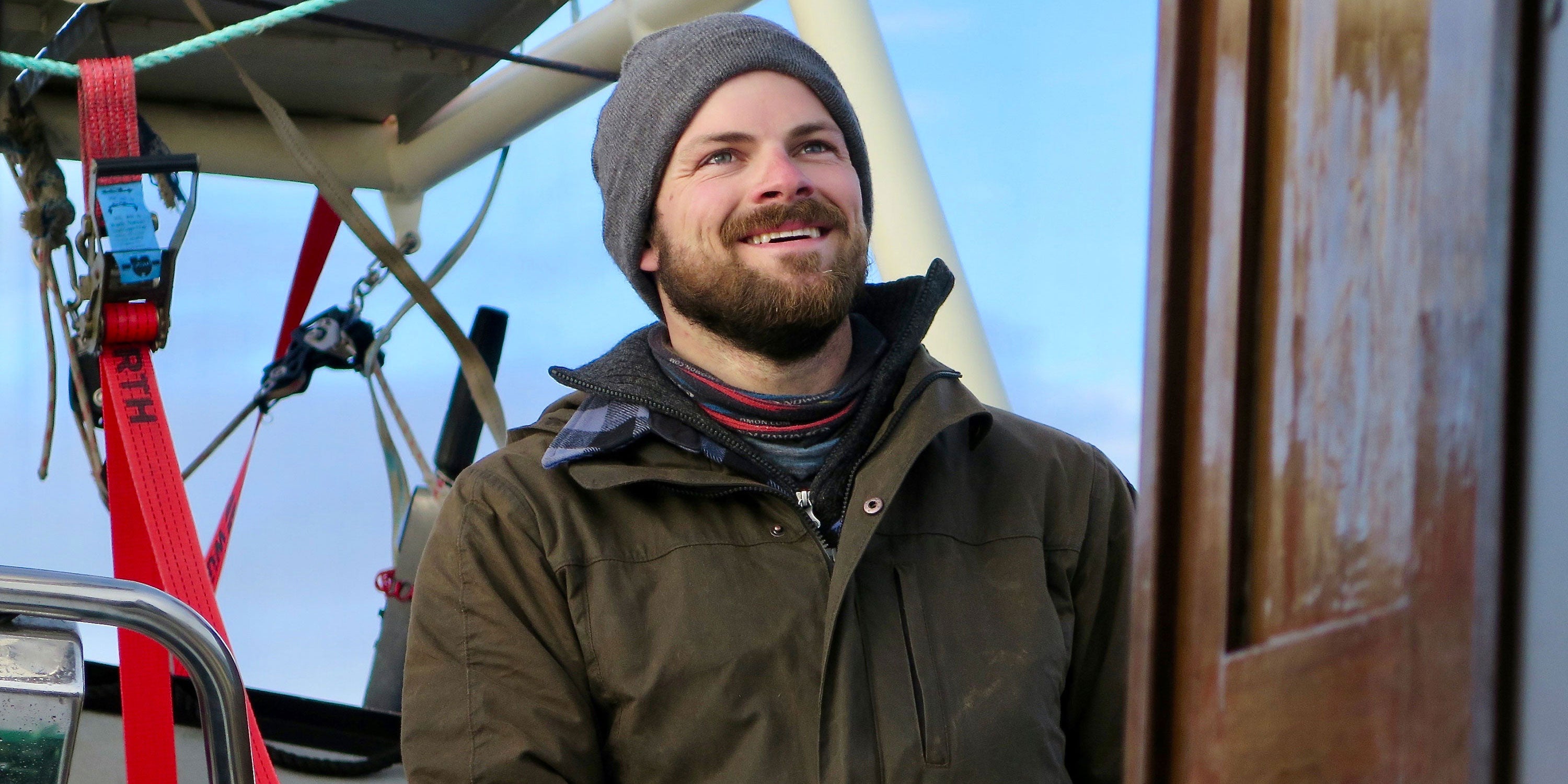 Man sailing boat wearing waxed Cotton Trail jacket closeup banner